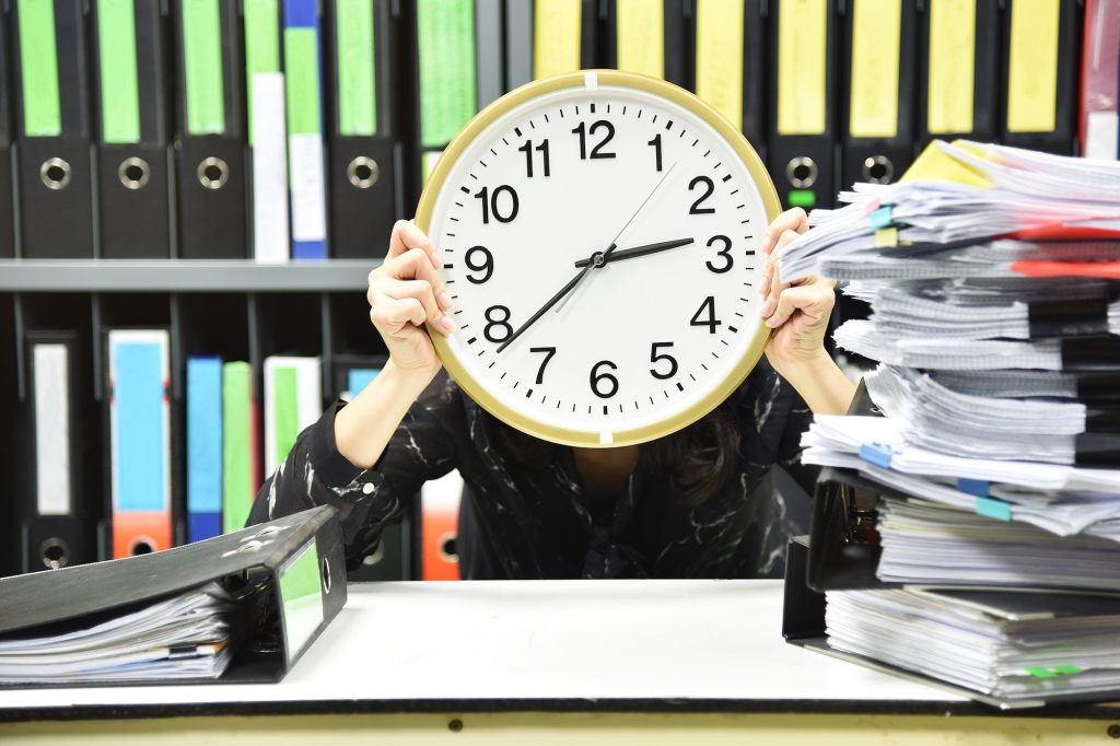 Office worker holding a clock, Working overtime and lot of work, Time management concept.